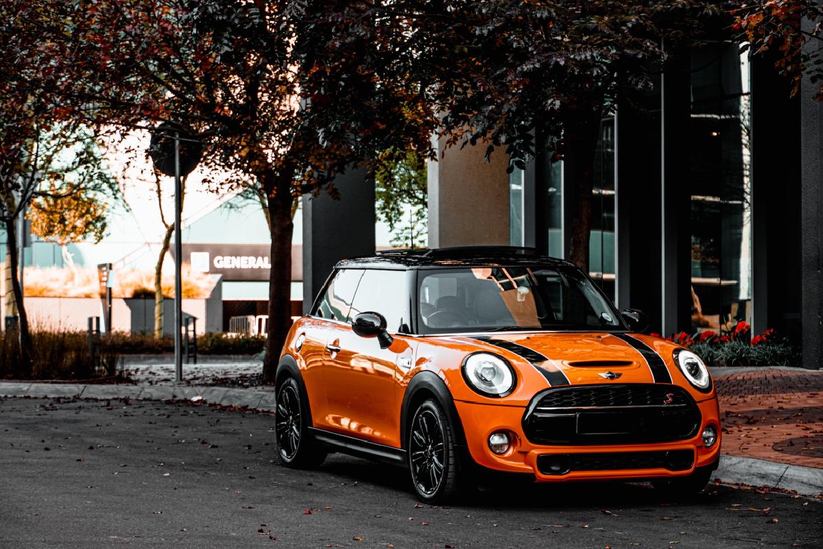 Ein oranger Mini Cooper, der auf der Seite einer Straße geparkt ist. Ein Symbolbild für die Autoversicherung in Österreich.