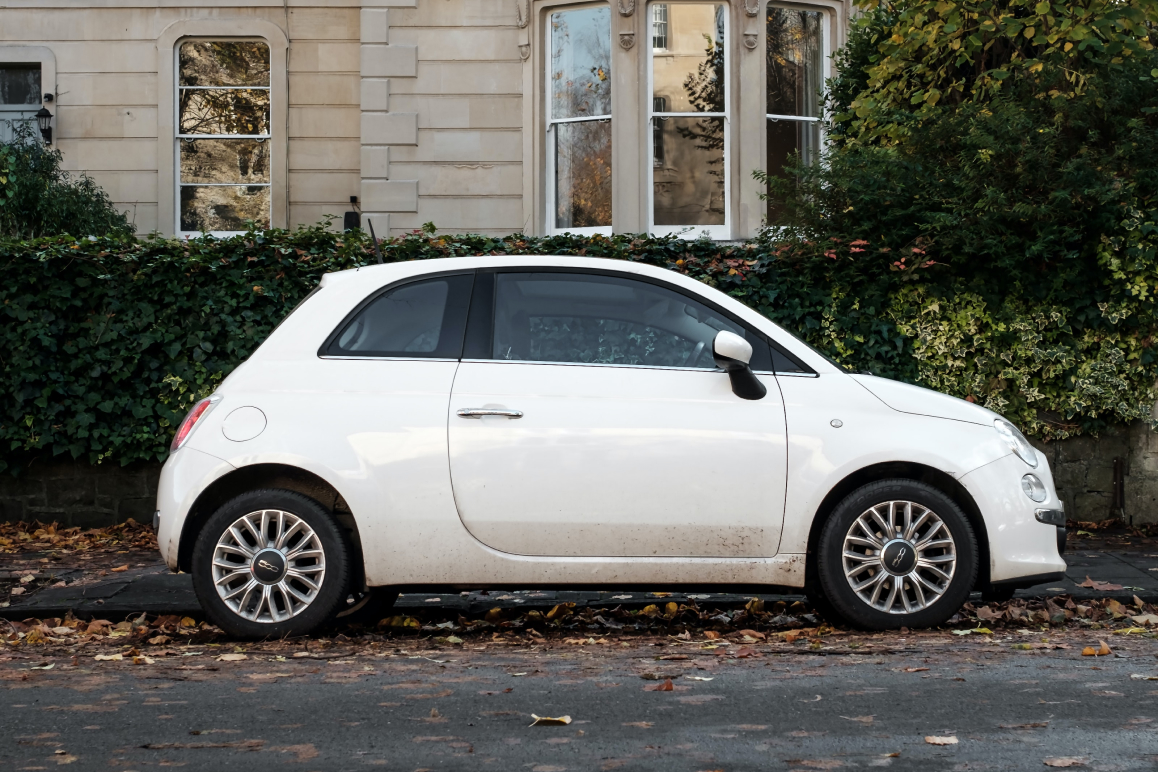 Ein weißer Fiat 500 steht im Herbst auf einer Straße. Das Foto ist von Oli Woodman.