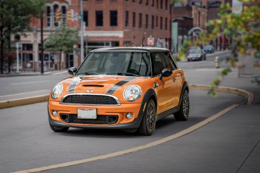 Ein oranger Mini Cooper, der auf der Straße geparkt ist.