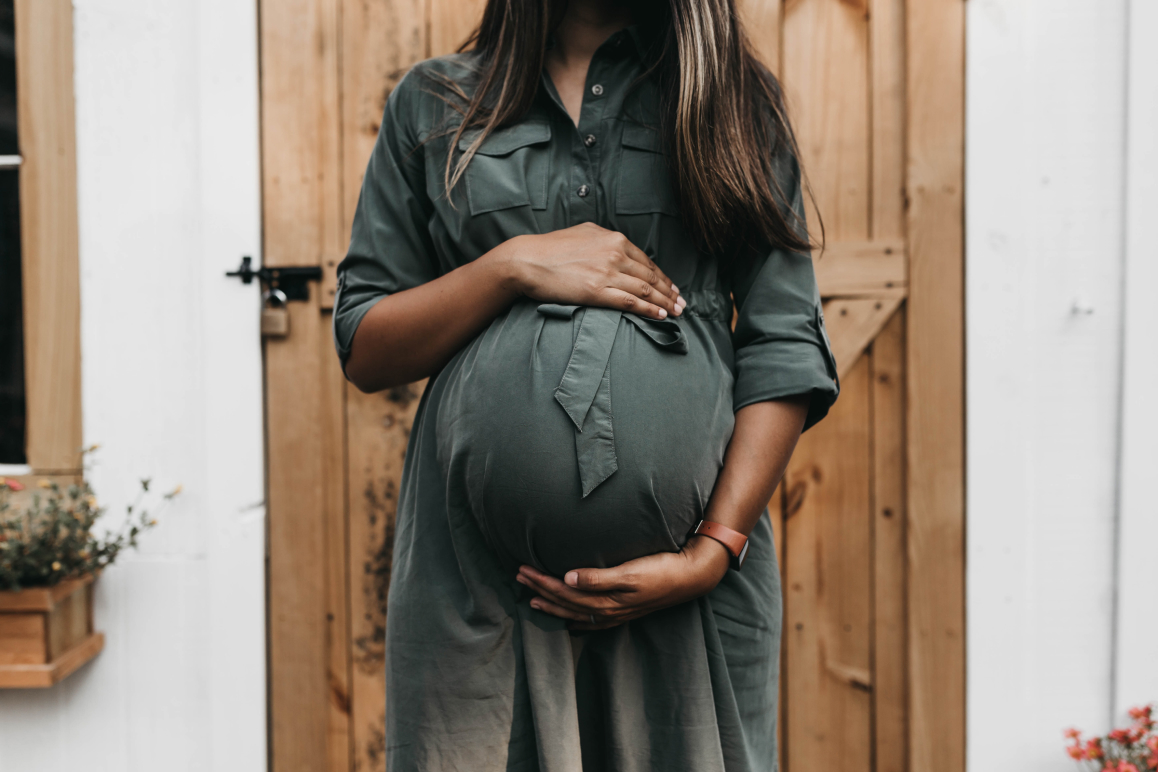 Eine schwangere Frau, die ihren Bauch hält.