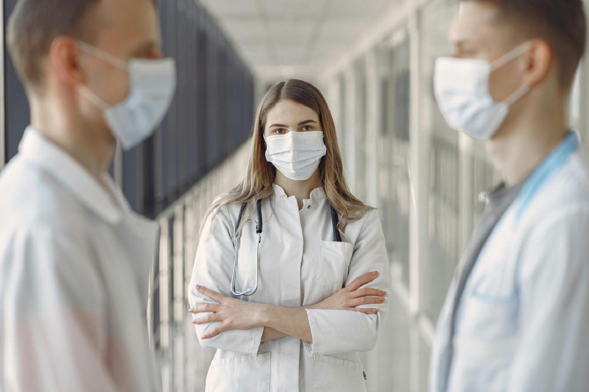 Eine Ärztin steht zwischen zwei Ärzten. Ein Symbolbild für die Unterschiede zwischen der gesetzlichen und der privaten Krankenversicherung in Österreich.