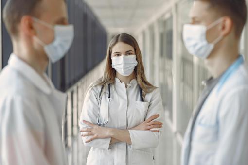 Eine Ärztin steht zwischen zwei Ärzten. Ein Symbolbild für gesetzliche vs. private Krankenversicherung - was ist besser?