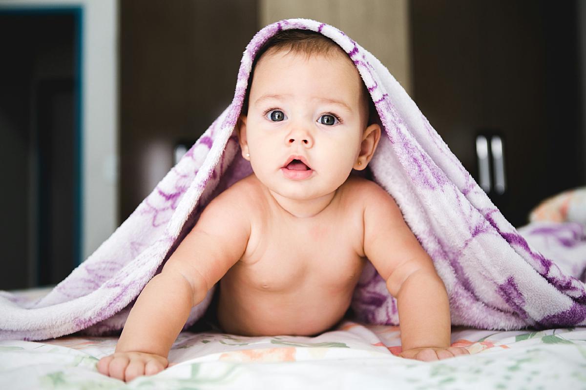 Ein Baby unter einer Decke. Ein Symbolbild für die Baby-Option der privaten Krankenversicherung. Durch sie bekommt auch ein Neugeborenes direkt nach Geburt eine Versicherung, ohne Gesundheitsprüfung.