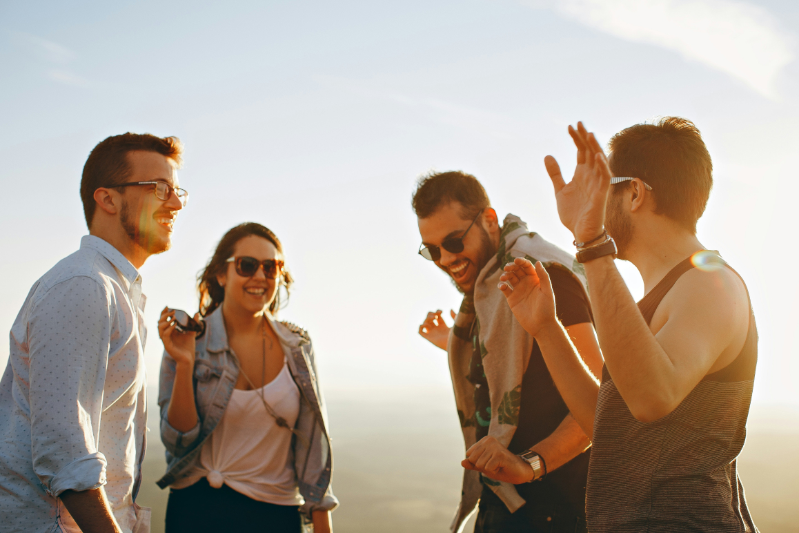 Vier junge Erwachsene, die lachen und sich freuen, weil sie eine günstige Krankenzusatzversicherung abgeschlossen haben.