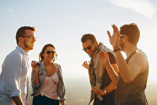 Vier junge Erwachsene, die lachen und sich freuen, weil sie eine günstige Krankenzusatzversicherung abgeschlossen haben.