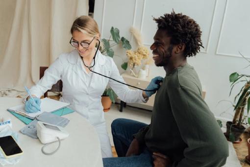 Ein Mann, der sich von einer Ärztin im Krankenhaus in der Sonderklasse behandeln lässt und glücklich ist, dass er den Selbstbehalt für die private Krankenversicherung richtig gewählt hat.