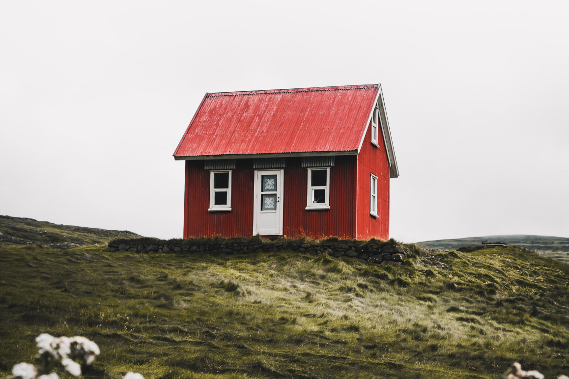 in kleines rotes Haus, das auf einem Hügel steht.