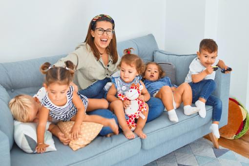 Eine Mutter und ihre Kinder sitzen auf einer Couch. Durch die Versicherungs-App Sophia hat Mama die richtigen Versicherungen für ihre Kinder gefunden.