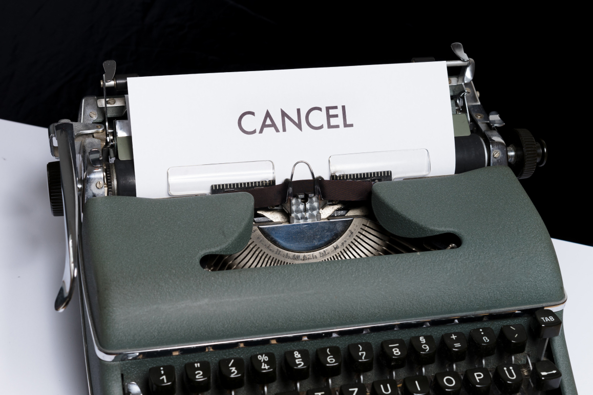 Eine dunkelgrüne Schreibmaschine mit einem Papier im Einzug, auf dem “Cancel” steht.