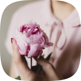 Ein Foto von einer Frau, die eine Blume hält, das die Kostenerstattung einer Hebamme von der Privatarzt-Versicherung symbolisiert.