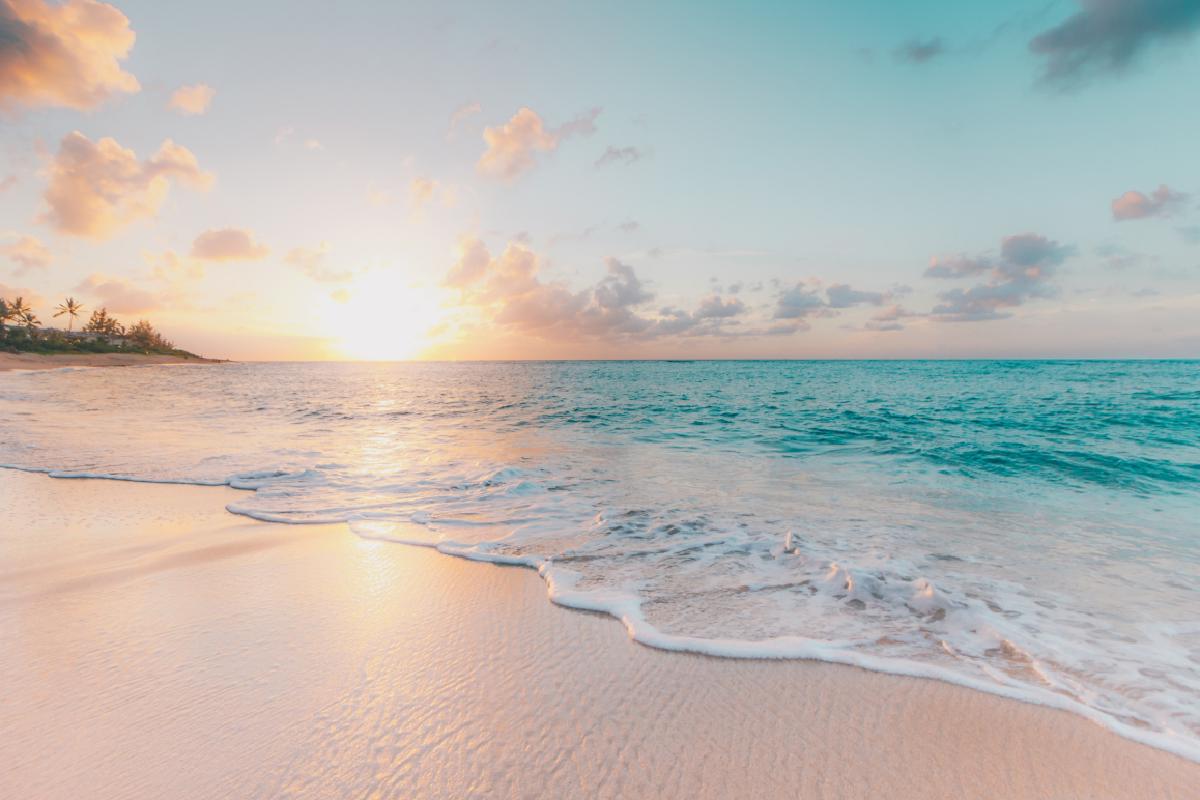 Das Meer auf Hawaii, bevor die Sonne untergeht. Ein Symbolbild für die Reiseversicherung in Österreich.