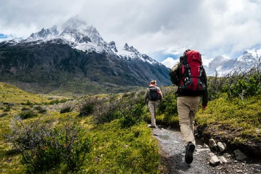 Eine Frau und ein Mann, die in den Bergen wandern. Beide sind über eine Unfallversicherung abgesichert. Sie haben die Versicherung über die Versicherungs-App Sophia gefunden.